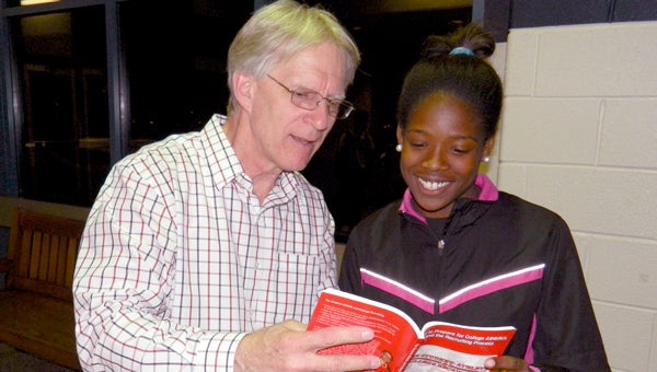 Rick Wire shows Lakeland sophomore track athlete Teahney Walker his book, “The Student-Athlete and College Recruiting,” after his seminar on Monday at Lakeland High School.