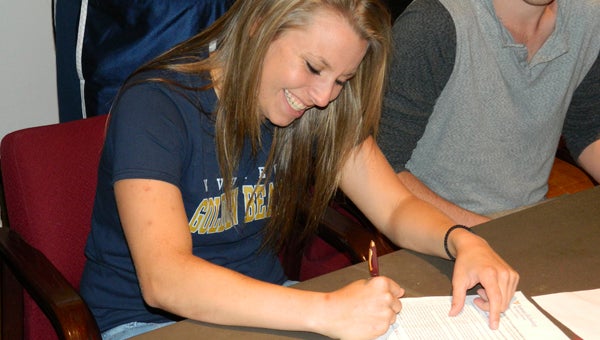 King's Fork senior softball player Kayla Harbin signs with West Virginia University Institute of Technology during a recent ceremony at King's Fork High School, as family, friends and coaches look on.