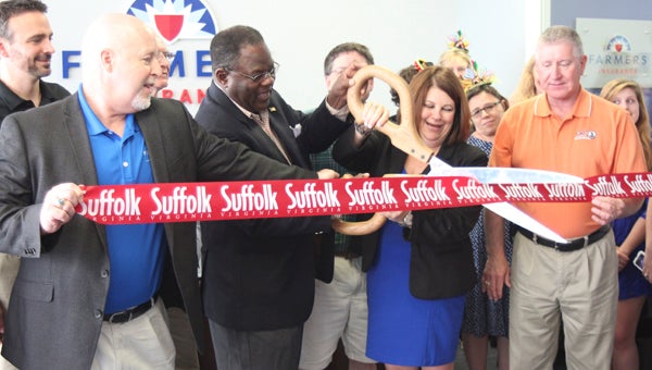 At Vicki Warren Agency in North Suffolk, Bill MacArthur, district manager for Farmers Insurance, holds one end of the ribbon, helping Charles Brown, Suffolk’s vice mayor; Vicki Warren, the agent; and Councilman Roger Fawcett officially open the new location Thursday.
