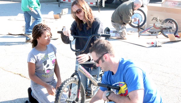 During a build-a-bike event at Chesapeake Square on Saturday, Jennifer Berow and Jason Greer help Desarae Branch with some final touches on assembling her new bike. Employees at Golden State Foods’ Suffolk location contributed to the GSF Foundation’s effort to fund 125 bikes.