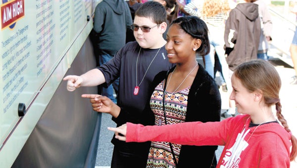 At King’s Fork Middle School on Tuesday, John Yeates Middle School sixth-graders Michael Cain, Nevaeh Herndon and Vienne Aberle read about the Tuskegee Airmen’s six principles, spelled out on the side of the Commemorative Air Force Red Tail Squadron’s traveling exhibition trailer.