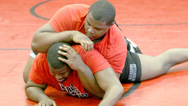 Nansemond River High School freshman Dia Gray, top, wrestles his older brother, Demetrious Gray, who helped coach him to the heavyweight MAWA national title.