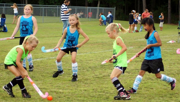 Jordyn White hits the ball as her twin sister and teammate, Aubrey, second from right, observes.  Kaleigh Bibbo, standing between them, advances, as does Annie Copeland, far right, during Monday's youth division (ages 6-8) game at Lakeland High School.