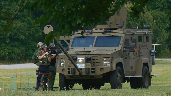 Donna Perry Photo Police take cover behind an armored personnel carrier while firing teargas into a home on Walter Reid Drive across from Elephant’s Fork Elementary School during a barricade situation on Monday. A suspect, Gary Abernathy, is believed to have taken his own life at the end of the day.