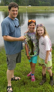 Aaron Duman, a best friend of the tournament's namesake, holds a catch he got during Saturday's second annual Thomas J. O'Connor IV Memorial Fishing Tournament at Johnson's Gardens. He was joined by his daughter Bradleigh, far right, and family friend Caroline Morgan.