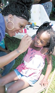 Shalaria Bolques paints a butterfly on 4-year-old Harmonie Eley’s face at the Heritage Acres apartments community day hosted by St. Mary Church of God in Christ on Saturday.