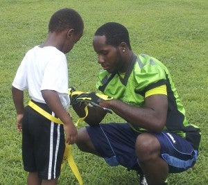 Suffolk Chargers defensive back Andre “AJ” Harper helps Damarrion Madison get prepared in a flag football game during the Peanut City Football Camp last year. Norfolk State University coach Donald Hill-Eley plans to bring former players to help him run the camp this year. (Angela Harper photo)