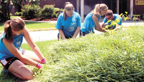 On Monday, Michelle West, Madison Morrissette, Cameryn Bass and London Violette clear a garden bed of weeds at Kilby Shores Elementary School, as part of Southside Baptist Church’s Serve the City ministry.