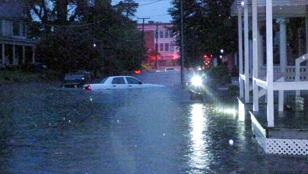 Partially submerged cars on downtown’s Clay Street float as a firefighter with a flashlight makes his way back up the street Thursday evening. Strong thunderstorms deluged the city and rendered several roads impassable, with many vehicles being taken victim.