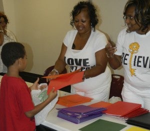 Lisa Rountree and Tillery family friend Shante Hall hand out school supplies to needy children during a Tillery Cousins Weekend community service event on Saturday in Suffolk.