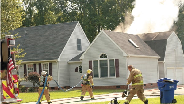 Firefighters pull hoses toward a house fire on Crittenden Road Monday morning. The house was unoccupied, and no injuries were reported.