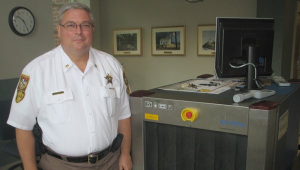 New uniform: Maj. Everett “E.C.” Harris demonstrates the security equipment at the entrance to the Mills C. Godwin Courthouse. In his new position, he is in charge of courthouse security and other aspects of the operation of the sheriff’s office.