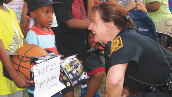 Suffolk Police Lt. Janet Brandsasse talks to children who won prizes in a basketball-shooting contest at the Lakeside-West End Civic League National Night Out celebration, including 3-year-old Carlos Ward III, in the striped shirt.