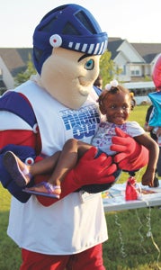 Nat Knight, the National Night Out mascot, holds 4-year-old Kayla Pattle at the Belmont Park National Night Out celebration. 