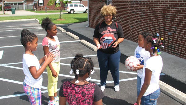 Volunteer Jenay Wolfrey leads children at Oak Grove Baptist Church and SCM Vision’s summer enrichment program on Wednesday in a game of “hot potato.” Pictured clockwise from Wolfrey are Adria Powell, Janasia Riddick, Ti’Mya Kearney, Mikayla Stagg and Keneja Davis.