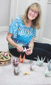 Psychotherapist Chris Gilchrist sits on the floor of her office in Western Branch with a few of the thousands of origami cranes that will symbolize healing and hope during the ninth annual Out of the Darkness Community Walk in Virginia Beach.
