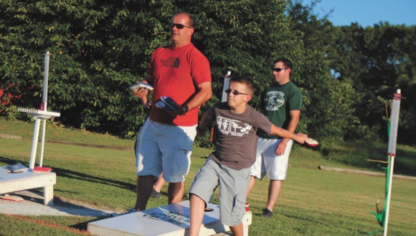 Darren and Hardman and 15-year-old son James perfect their toss during Driver Cornhole’s Wednesday tournament, which costs $2 per player and raises money for a variety of charities. This year, players are outfitting aircraft carriers with professional cornhole kits.