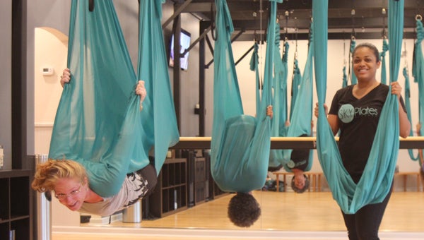 Jessica Gordon, who has opened an “aerial fitness” studio in Harbour View, supervises the acrobatic maneuvers of Colette Butler and Kimberly Jackson.