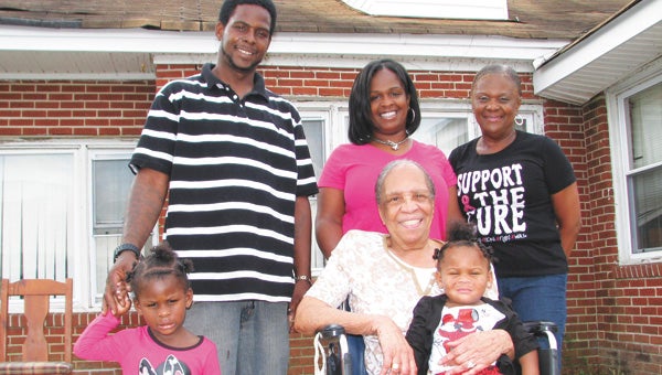 Members of the Boddie family stand in front of their family’s house that they will be renovating in memory of their lost loved one, Tiffany Renee Saunders-Boddie. Pictured in back are Tiffany’s husband, James Boddie; sister-in-law, Nichole Boddie-Kelly; and mother-in-law, Judy Lawrence-Lamb. In front are Tiffany’s children, Taylor, on left, and Maddie, in the lap of Lawrence-Lamb’s mother, Lucretia Lawrence.