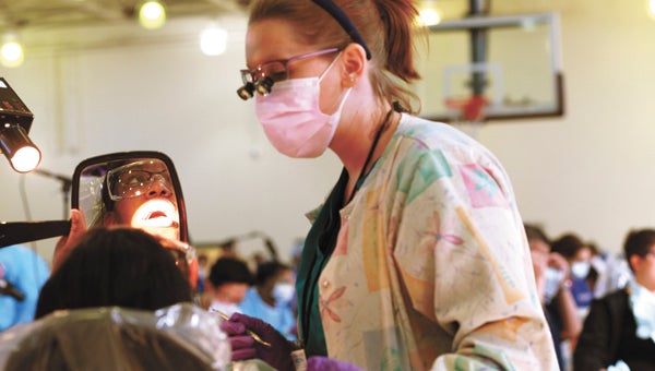 Dental hygienist Jennifer Fillman talks to 14-year-old patient Nona Towns about dental hygiene after cleaning Towns’ teeth at the Virginia Dental Association Foundation’s Missions of Mercy dental clinic in Suffolk last year. The second clinic will be held later this month. (File Photo)