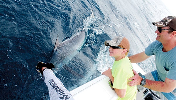 Nine-year-old Parker Blair of Suffolk poses next to the 250-pound blue marlin that he caught during the second annual Normal Man’s Offshore Fishing Tournament as Garrett Holden braces him.(Richard Blair photo)