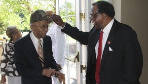 The oldest living graduate of Nansemond County Training School, 103-year-old B.J. Holland, is greeted at Saturday's reunion by another, somewhat younger graduate, Enoch Copeland, who is helping him remove his hat as he steps inside the Hilton Garden Inn.