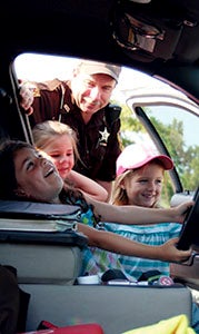 In the parking lot outside the Suffolk Family YMCA on Tuesday, Troy Babb, a Suffolk sheriff’s deputy, lets 5-year-olds Ashley Nicolet, Kylie Blanchard and Bella Laffey get behind the wheel of his cruiser.