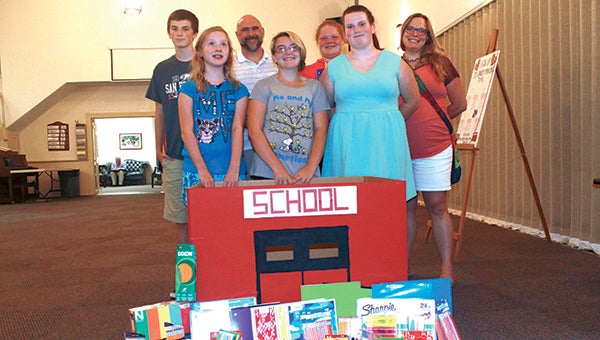 Hannah Carter, Kathleen Stump, Kimberly Curliss, Christina Carter, Abagayle Nelms, Jason Stump and Donald Curliss gather around the donation box for school supplies at Oakland Christian United Church of Christ.