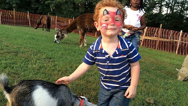 Tate Everett checks out a goat at the petting zoo at the Chuckatuck National Night Out celebration on Tuesday evening. Thousands of people from all over the city joined in their neighborhoods for the annual crime-fighting event.
