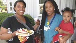 Soquia Blizzard, Simone Green and Jaceyon Ensley enjoy food and beverages during the National Night Out celebration at the Suffolk Redevelopment and Housing Authority headquarters on Tuesday.