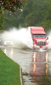 A tractor trailer sends up a huge spray as it crosses a flooded part of Constance Road on Friday afternoon. City officials eventually closed the road at this spot.