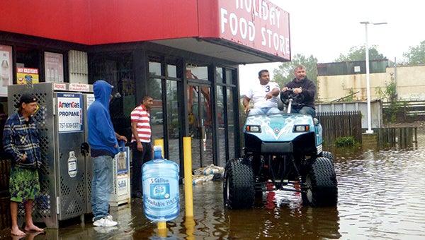 Mark Lester, owner of Carts Unlimited on North Main Street in Kimberly, pulls away from neighboring Holiday Food Store with owner Pritesch Patel on Friday afternoon. Lester was delivering sandbags to the store to help limit flood damge as the Nansemond River overwashed its banks at high tide. Patel said Friday was the first time the business had flooded since a nor’easter in 2013. Lester added, “You kind of get used to it.”