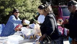 Zevetha Burr, a volunteer representing the Chesapeake Square Walmart, hands out canned goods at Impact Suffolk’s Thanksgiving giveaway on Saturday.