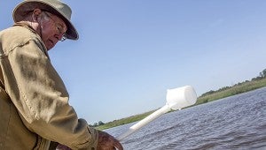 Nansemond River Preservation Alliance volunteer Brian Martin scoops a cup of water from the Nansemond River to check salinity levels.