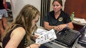 Suffolk Sheriff’s Deputy Debbie Callis creates an identification card for Layne Pace using Layne’s picture and fingerprints during the Suffolk Commonwealth’s Attorney’s forensics camp this week. Callis has worked with the forensics camp since it began in 2012.