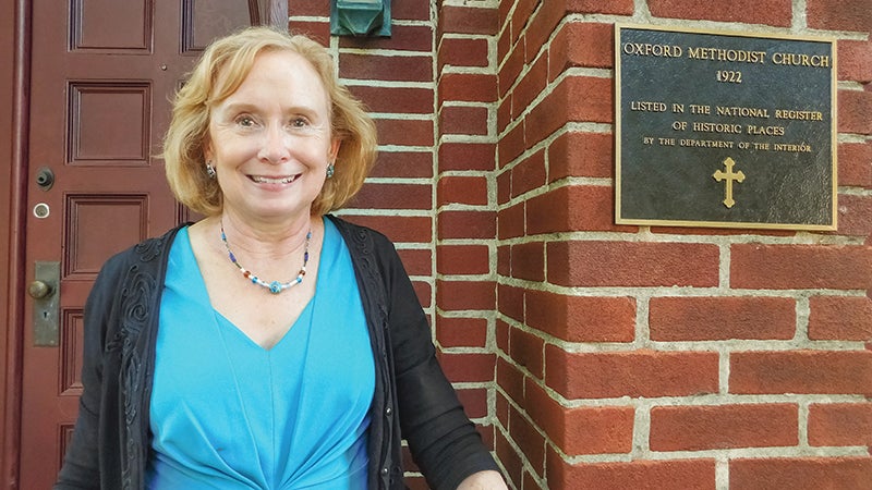 Katherine Hobbs, a member of Oxford United Methodist Church, stands by the newly installed plaque commemorating the church’s placement in the National Register of Historic Places. 