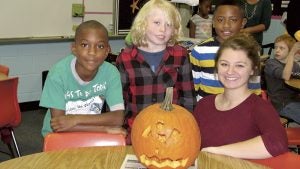 Kilby Shores Elementary School third-graders, from left, Antione Shepherd, Walker Douglas and Nizayer Bagley, show off the pumpkin they carved Monday with the help of Lakeland High School volunteer Autumn Thompson.